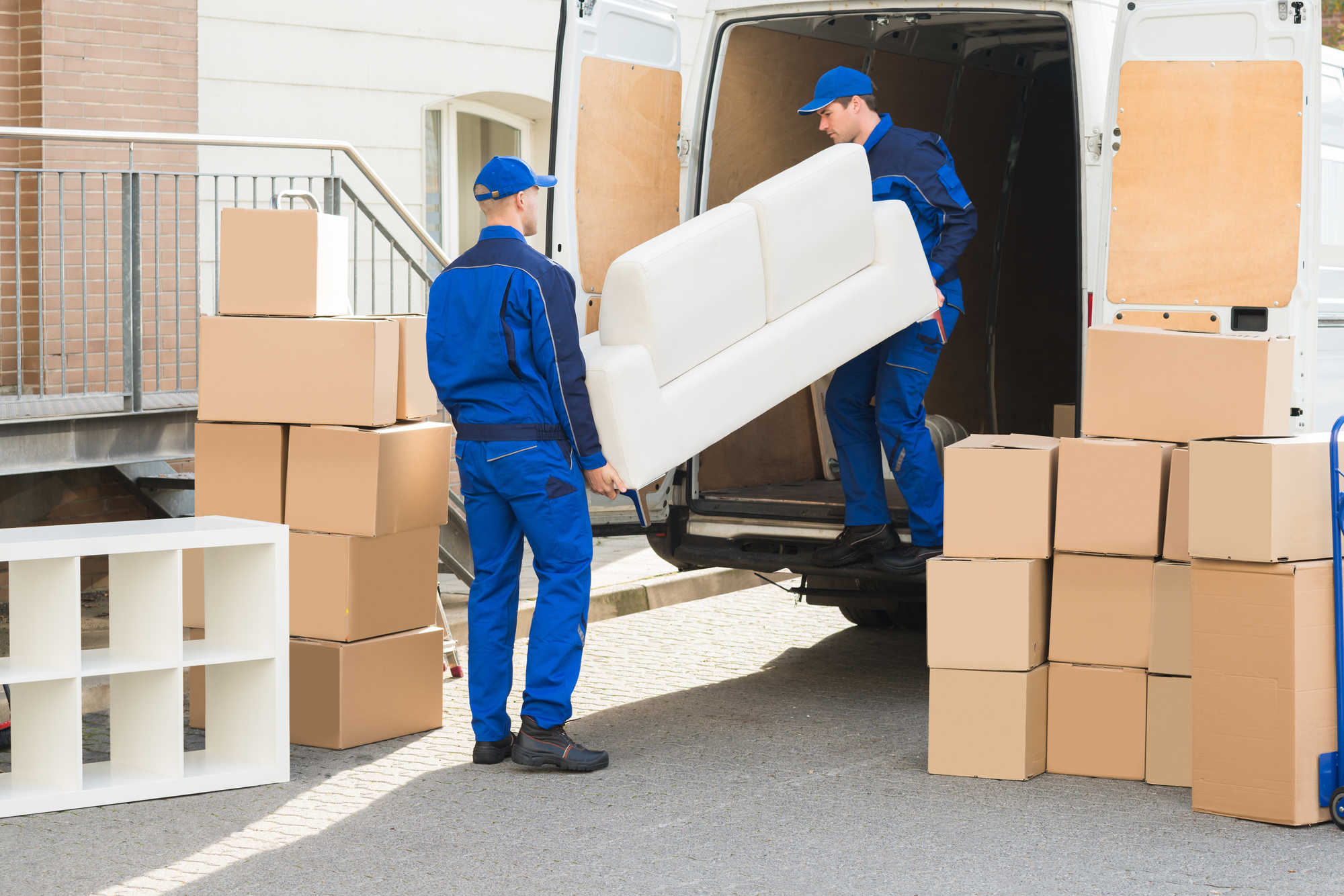 Two men unloading furniture from a moving truck, carefully handling it